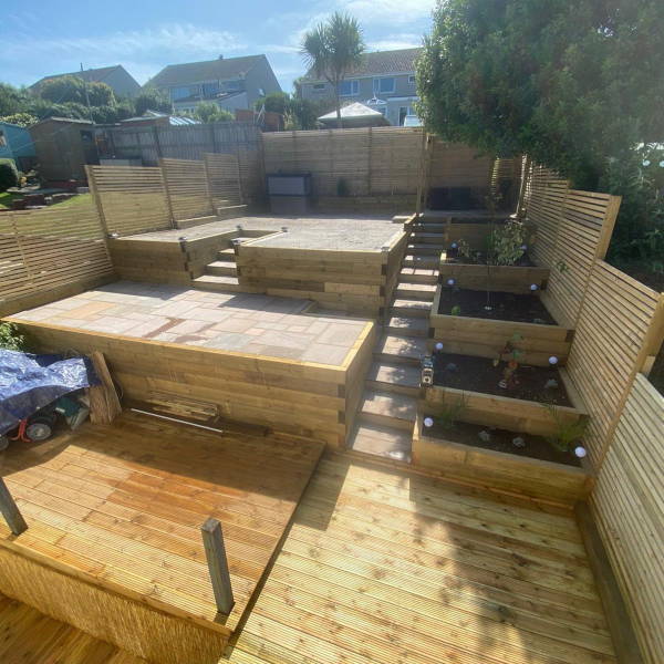 Multi-level wooden garden decking with steps and planter boxes in backyard